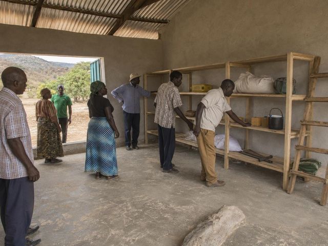 Community leaders and women farmers gather beside the newly built shelving during the storage hall orientation in Chepareria